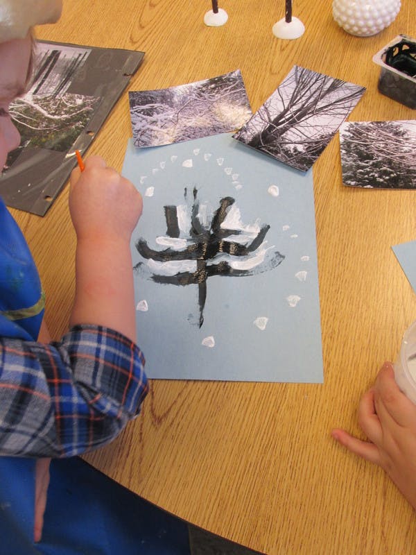 Child painting on light blue paper with black and white paint