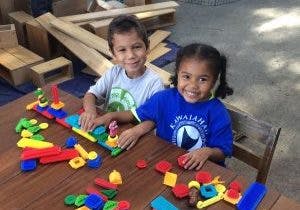 Two children playing with colorful building blocks at a table