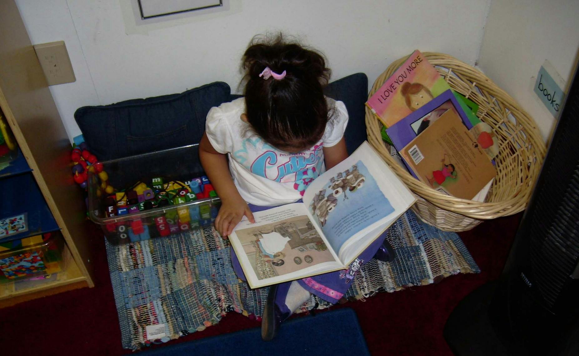 Child sitting on a cushion reading a book