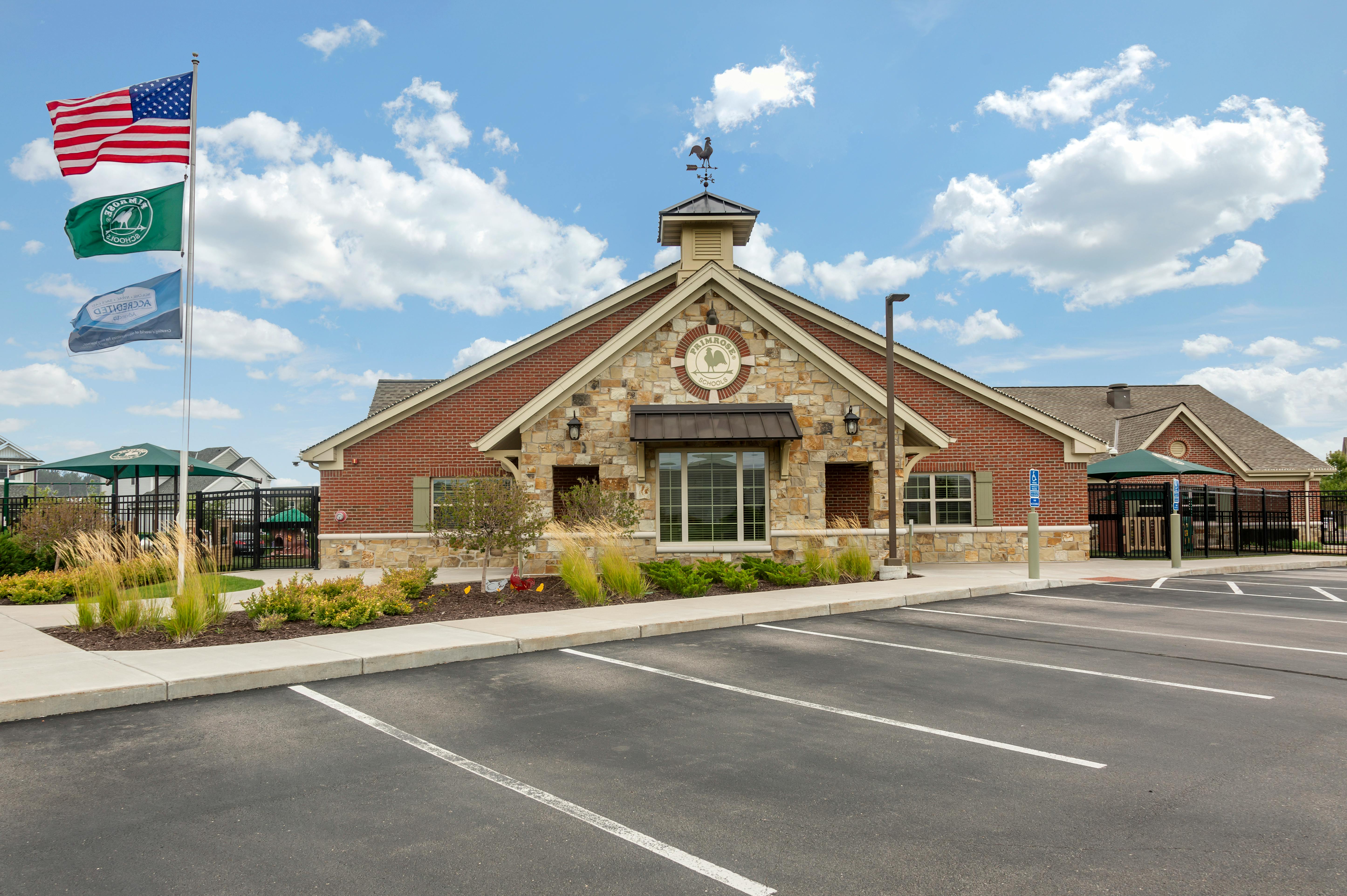 Brick and stone building with American flag, Primrose School flag, and accredited flag