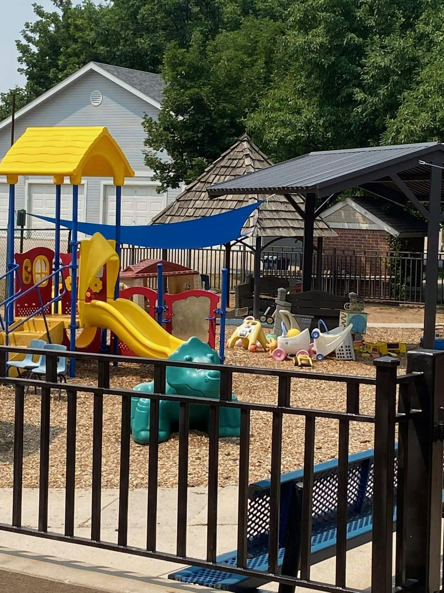 A children's playground with a yellow and red play structure and slides