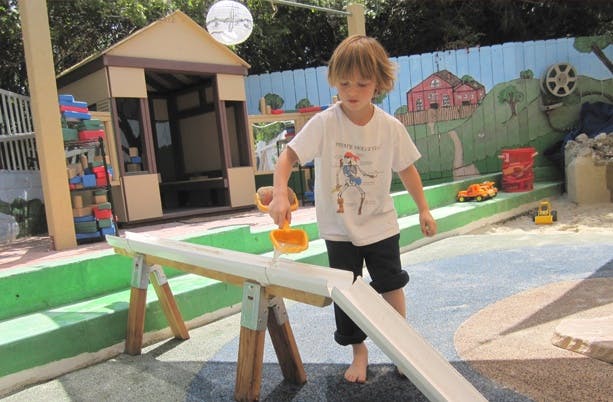 Child playing with a shovel and water in a trough