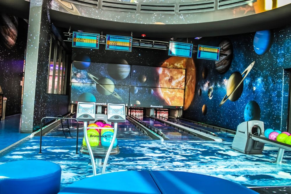 Bowling alley with space-themed decor and planets projected on the wall
