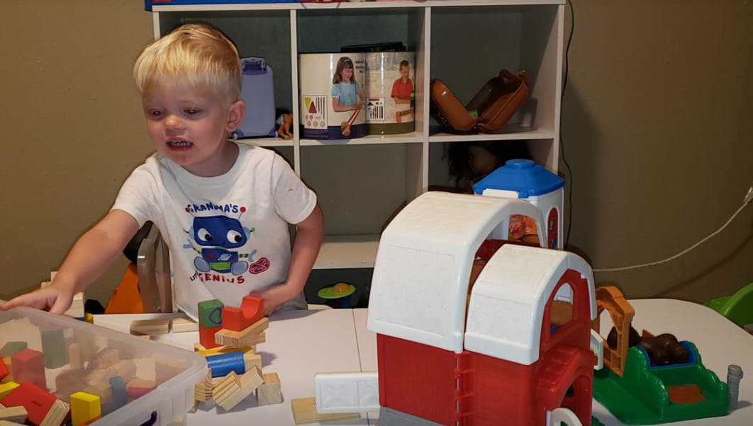 Child playing with building blocks and toy barn
