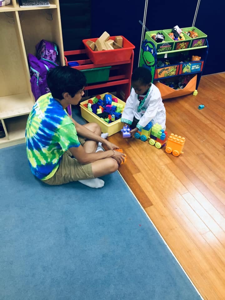 Two children playing with building blocks and toy trains on the floor