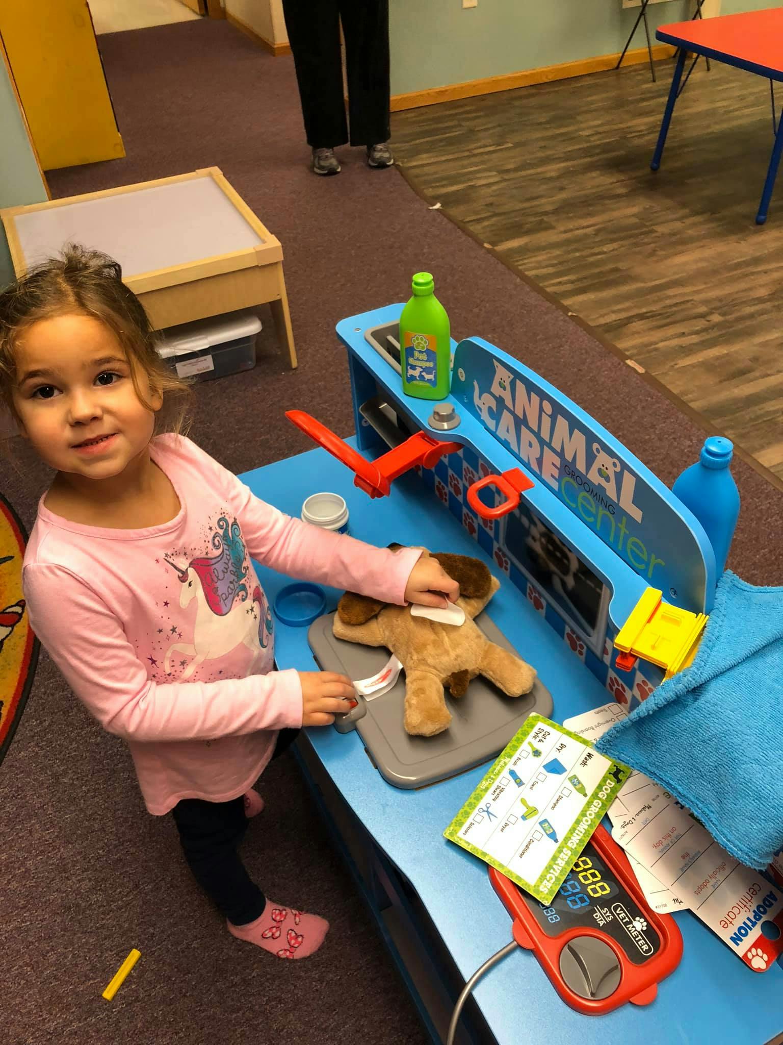 Child playing with a toy animal care center and stuffed dog