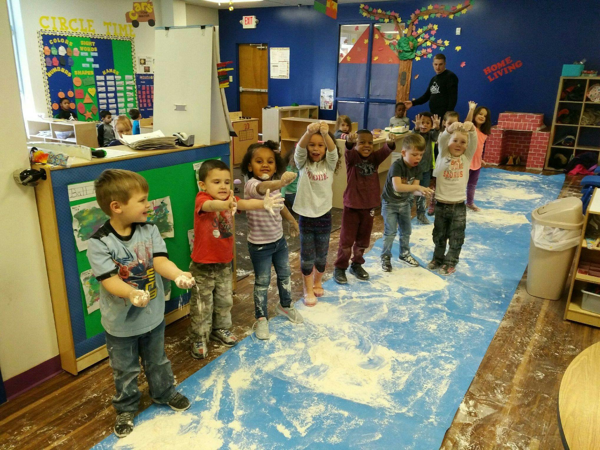 Children playing in a classroom with white powder on the floor