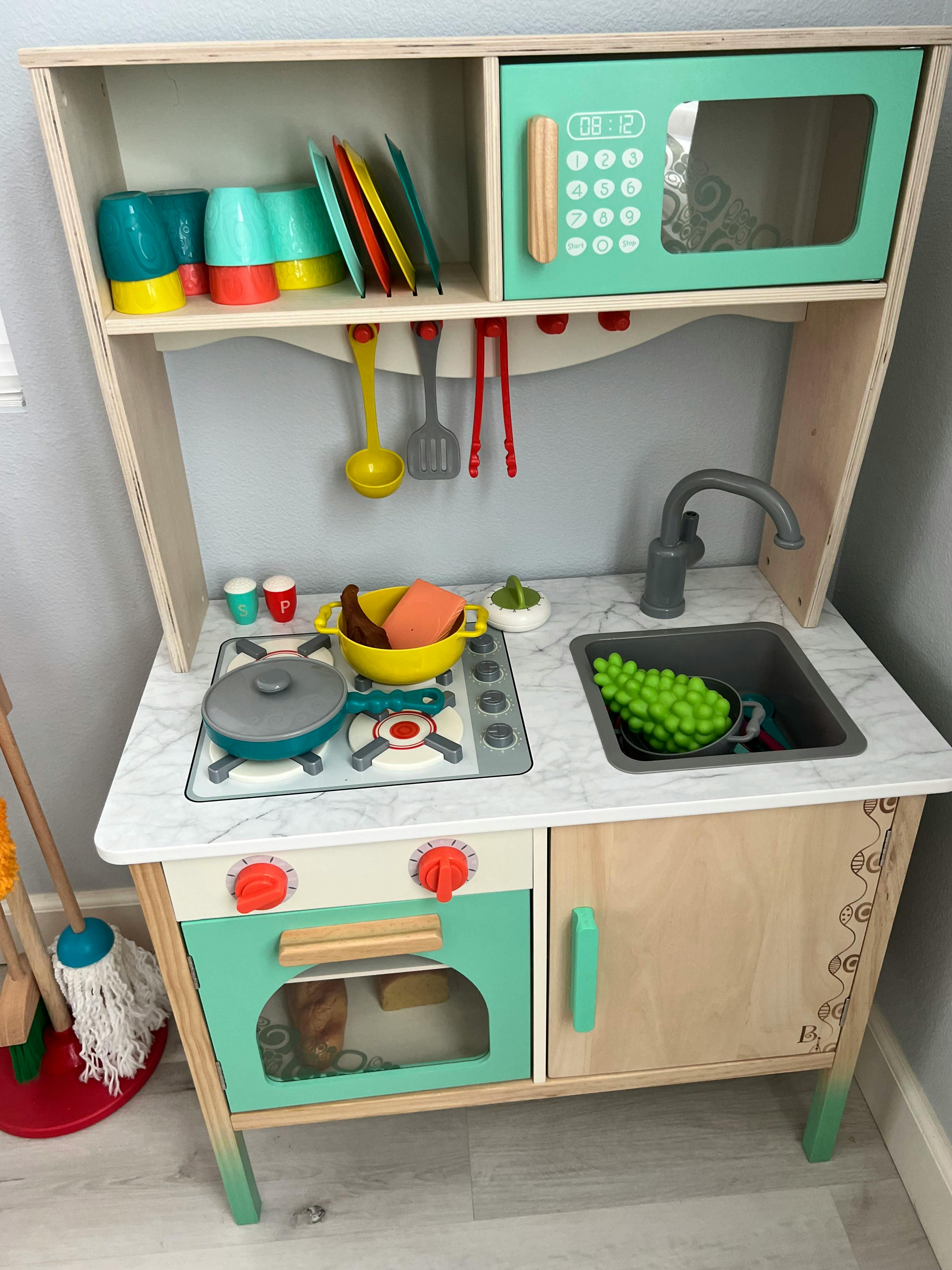 Child's play kitchen with stove, sink, microwave, and dishes