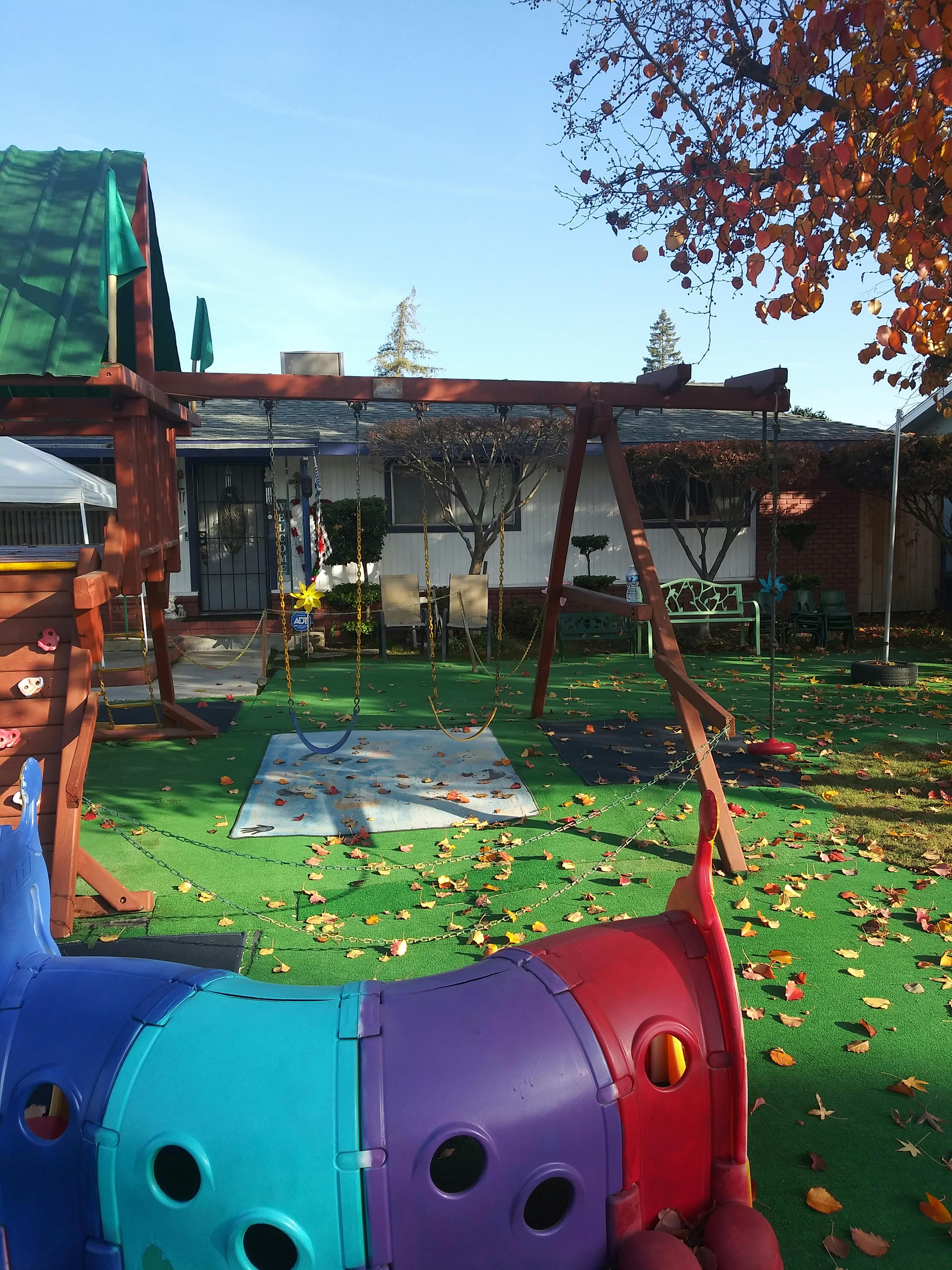 Backyard with a swing set, play structure, and colorful tunnel on the ground tunnel