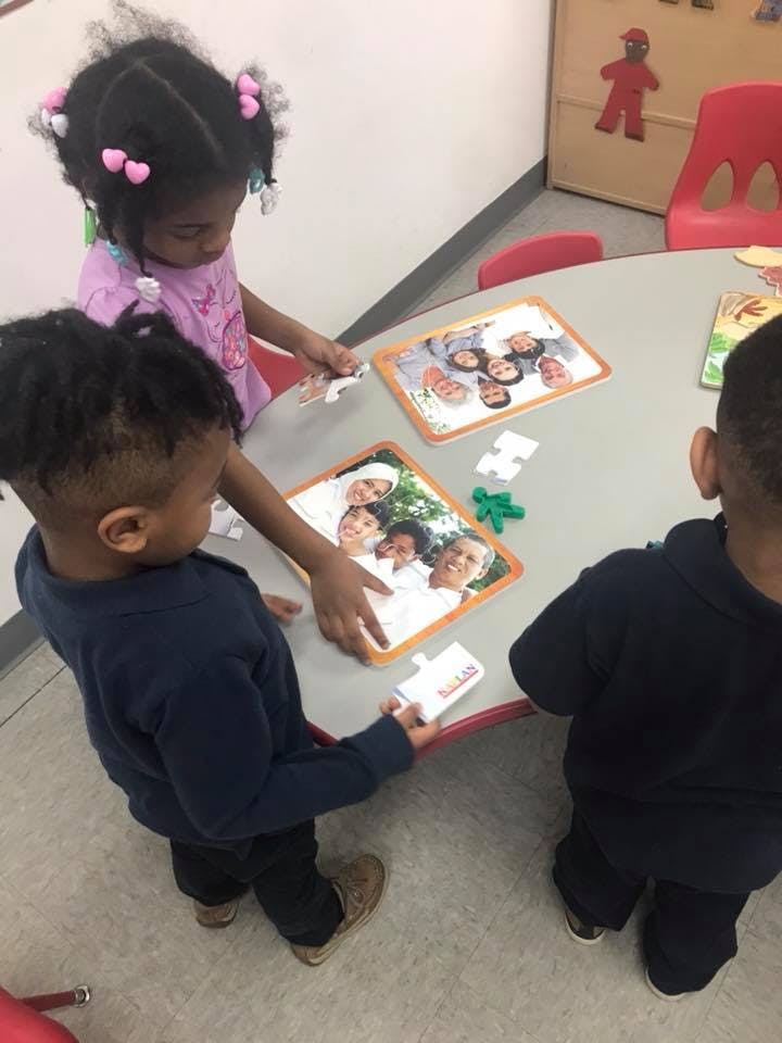 Three children playing with puzzles at a table