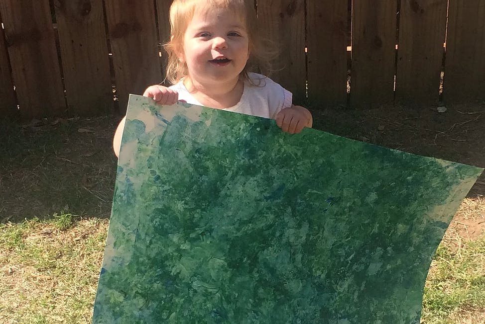 Child holding a large green sheet