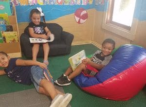 Three children reading books in a classroom