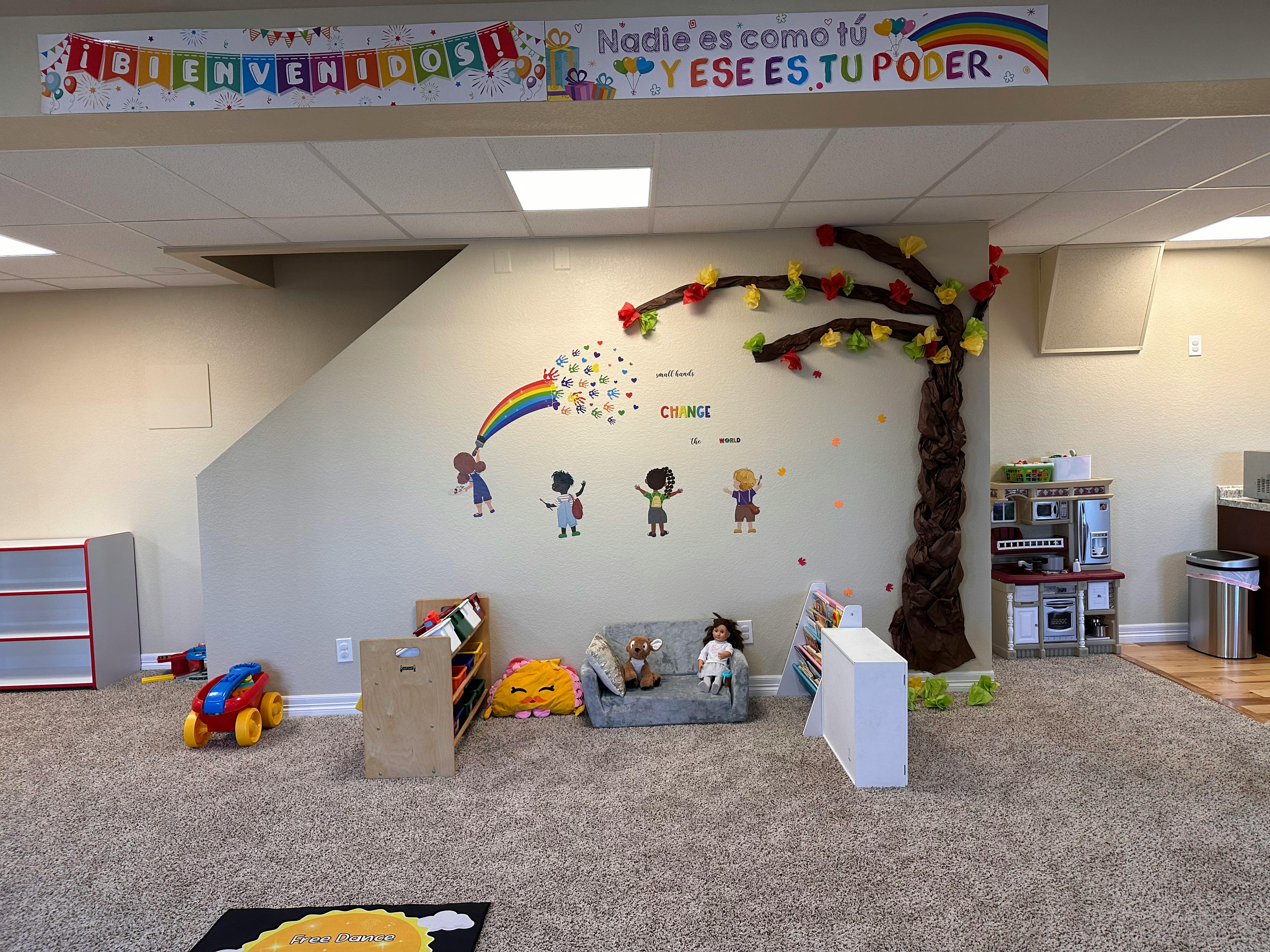 Playroom with wall decorations, toy kitchen, and small furniture