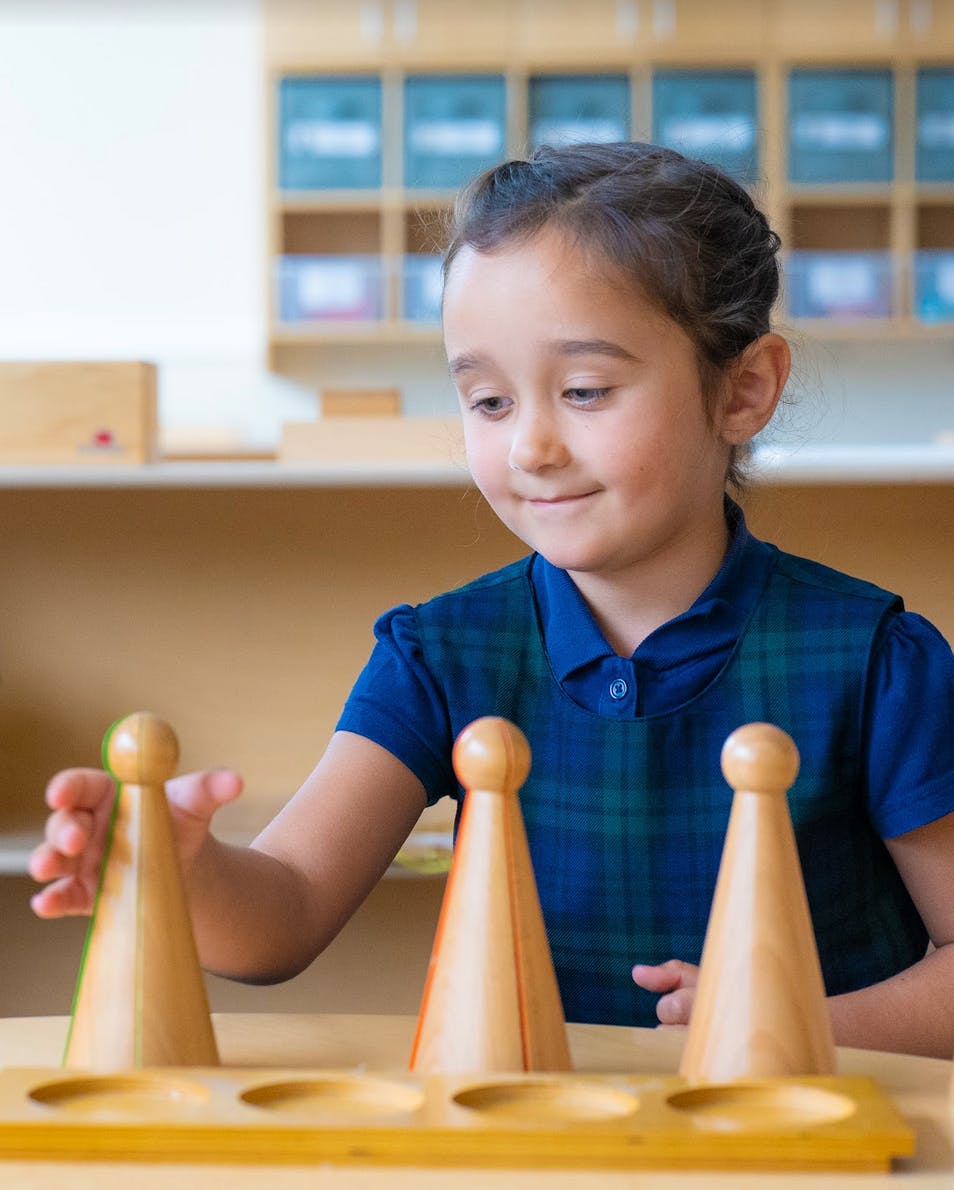 Child playing with wooden cone-shaped pieces on a table