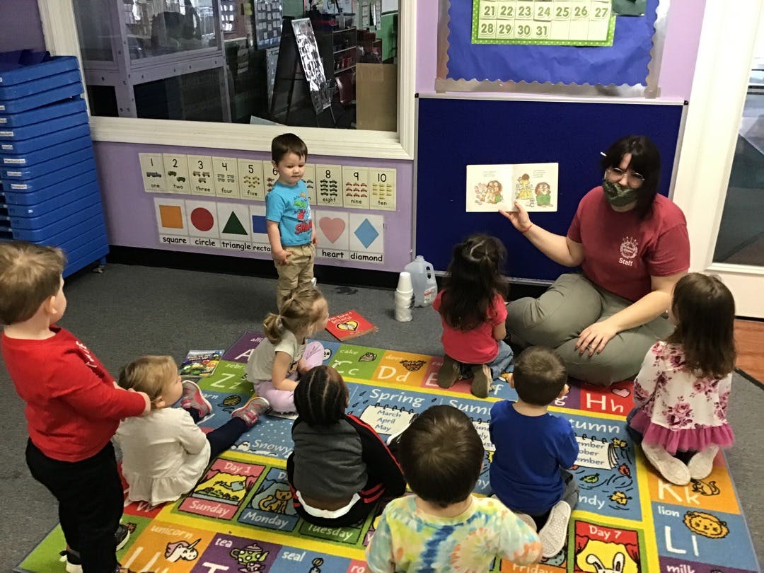 Adult person reading a book to children in a classroom