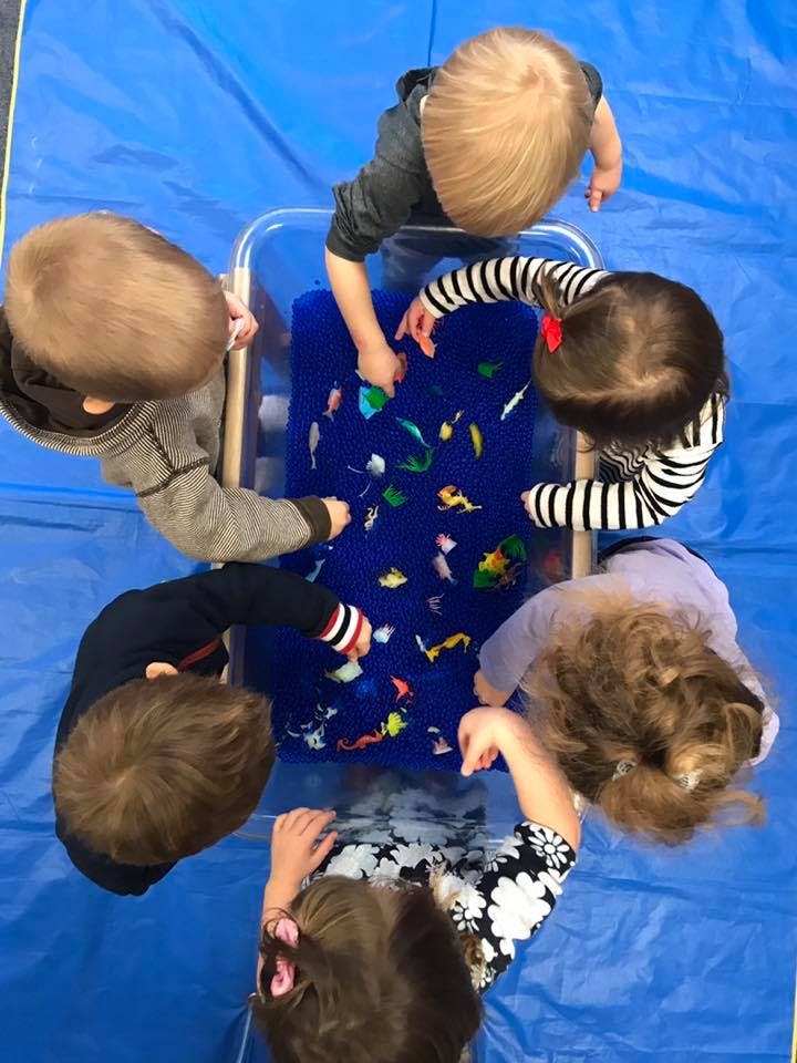Children playing with toys in a blue sensory bin