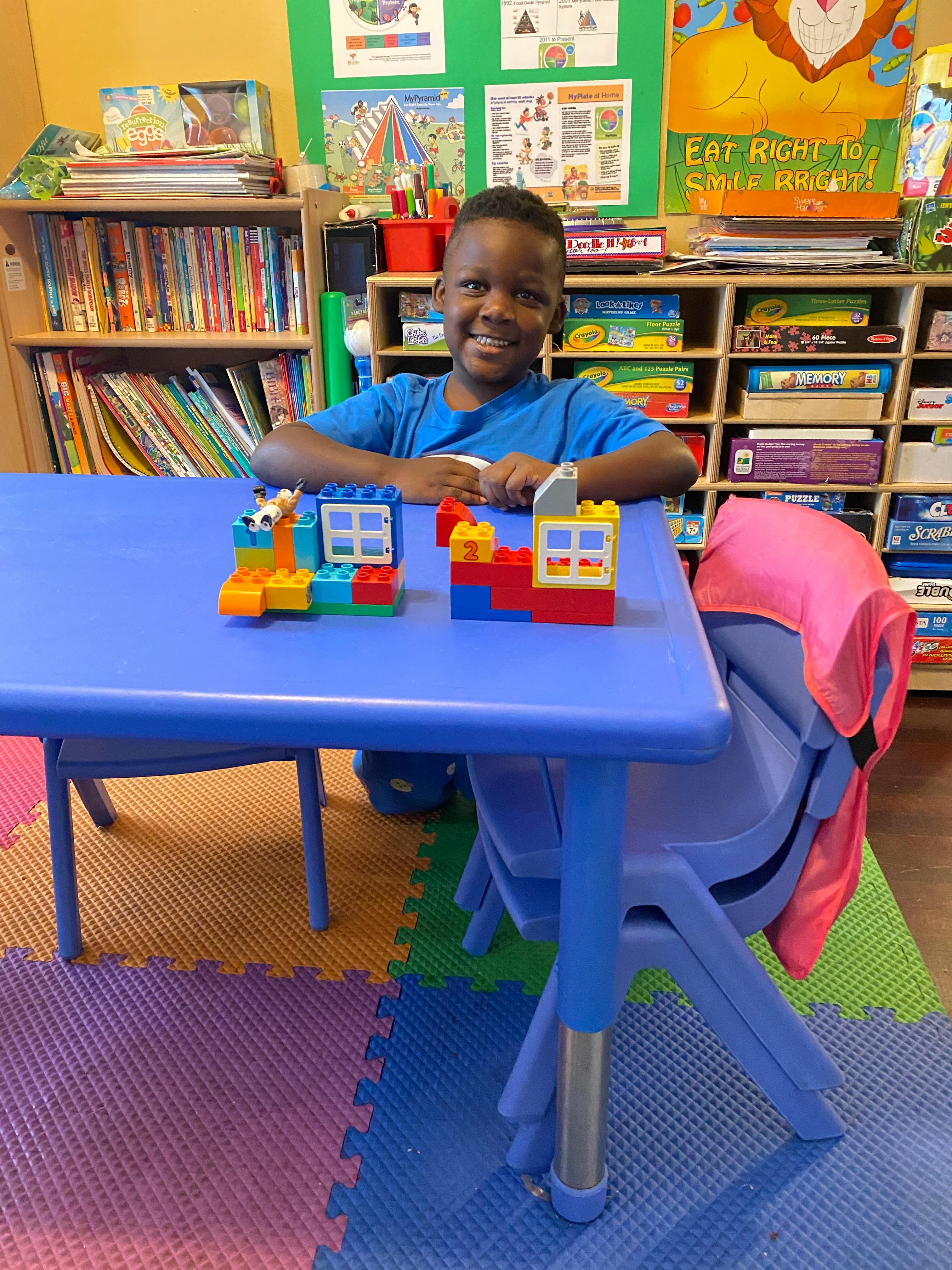 Child at a blue table with two block creations