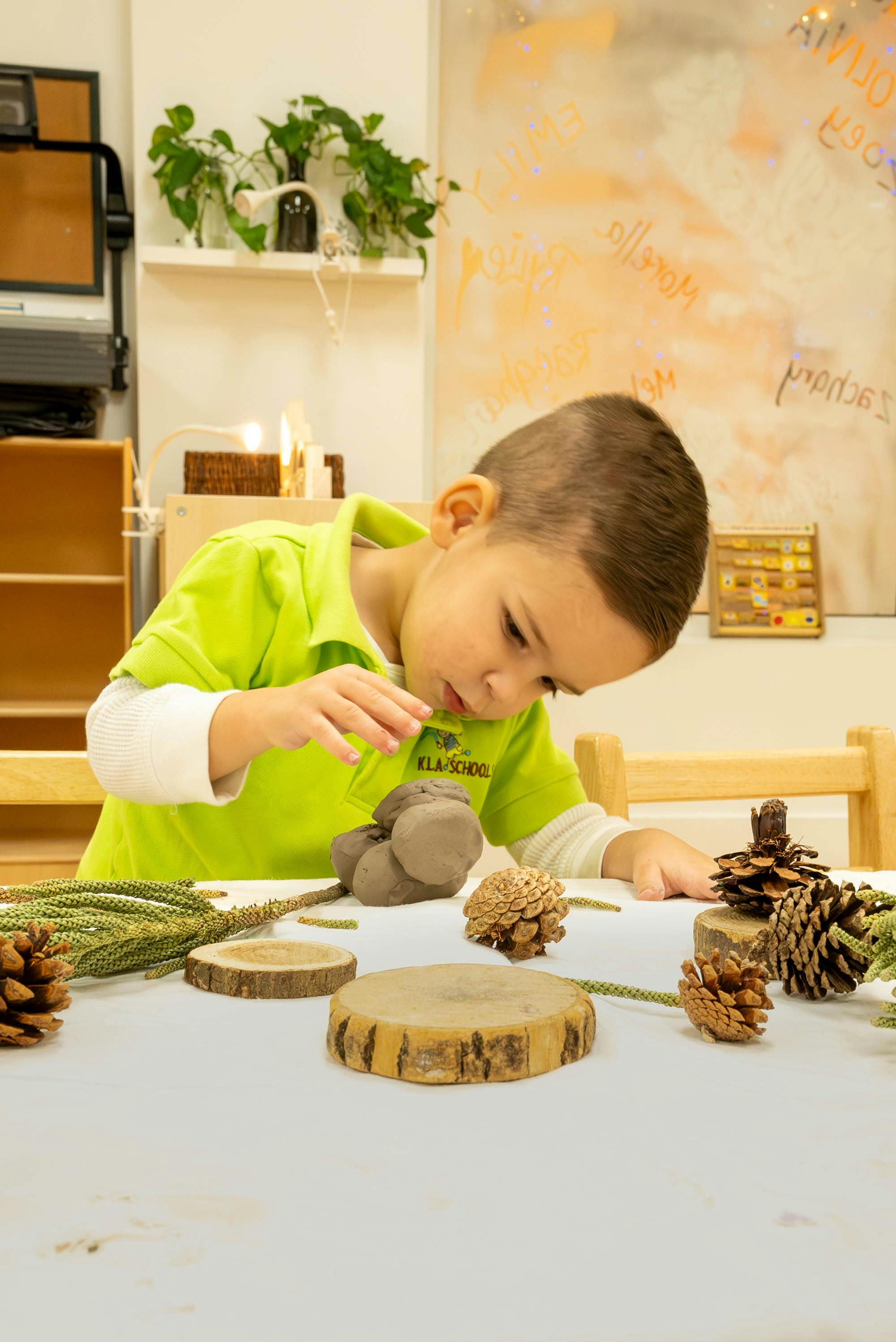 Child sculpting with clay and pinecones on a table