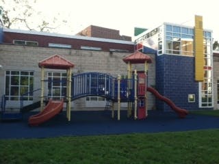 Playground structure with slides and climbing areas in front of a building