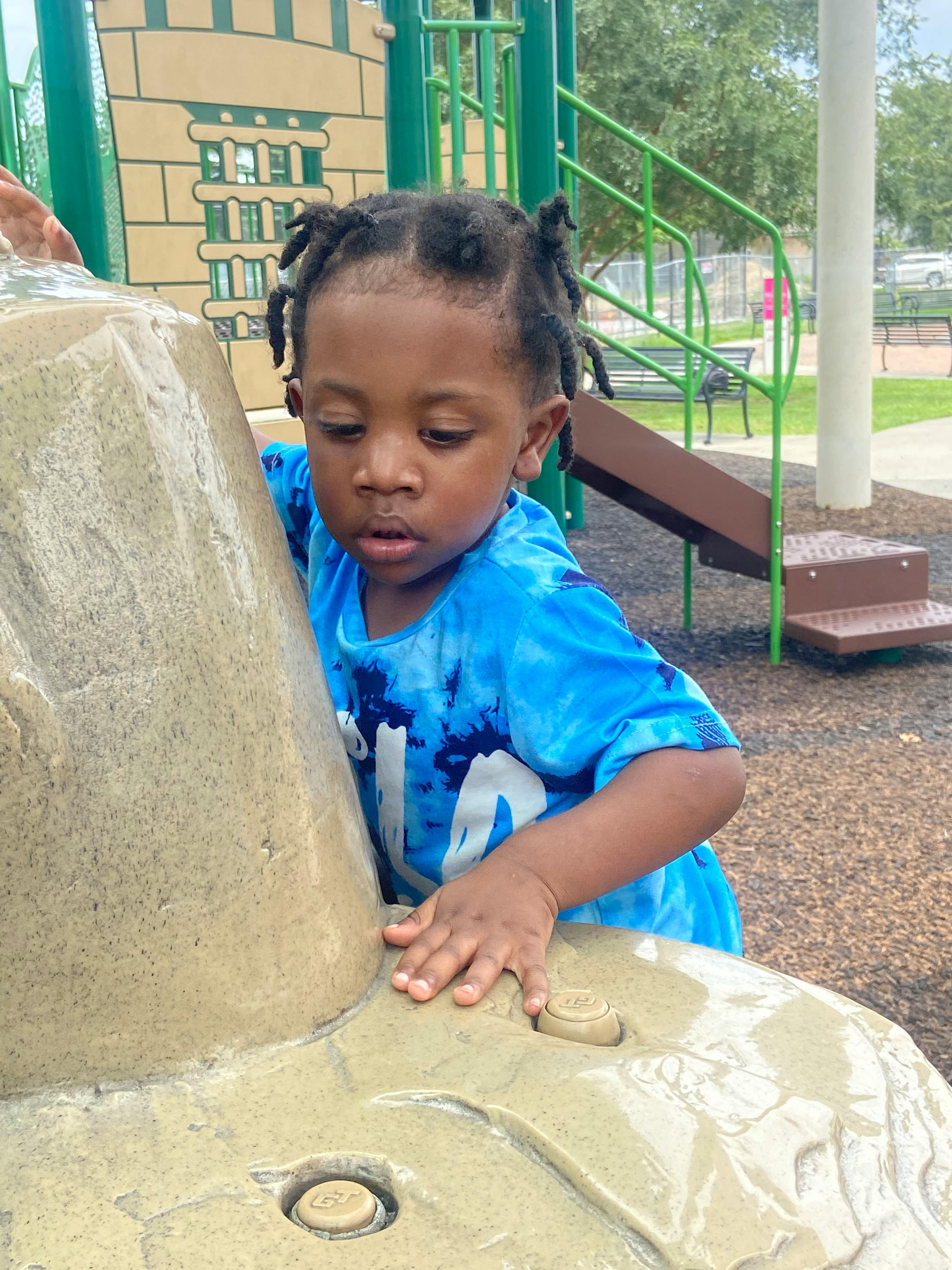 Child in a blue shirt on a playground climbing structure