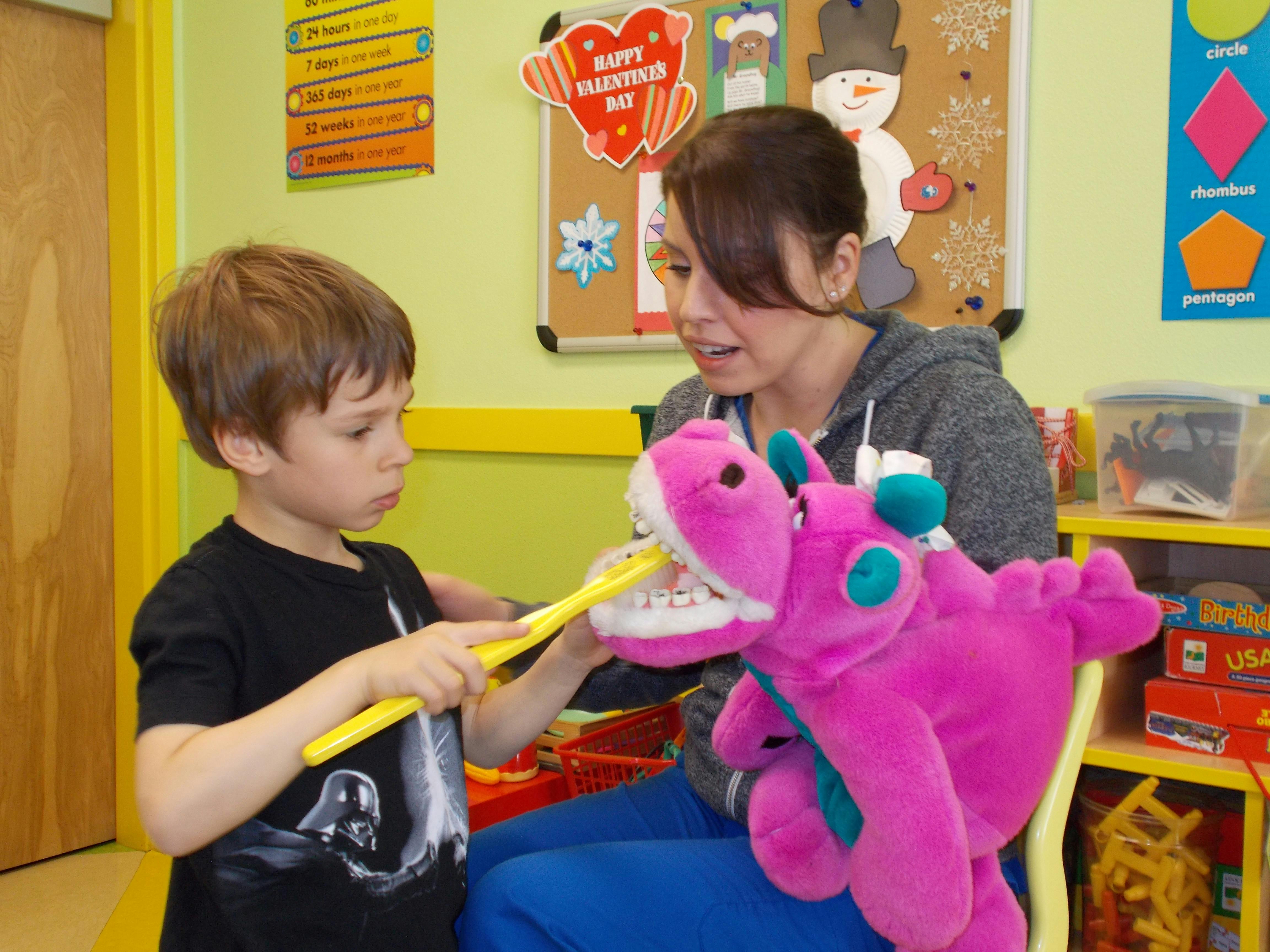 Child brushing teeth of a stuffed animal with a person