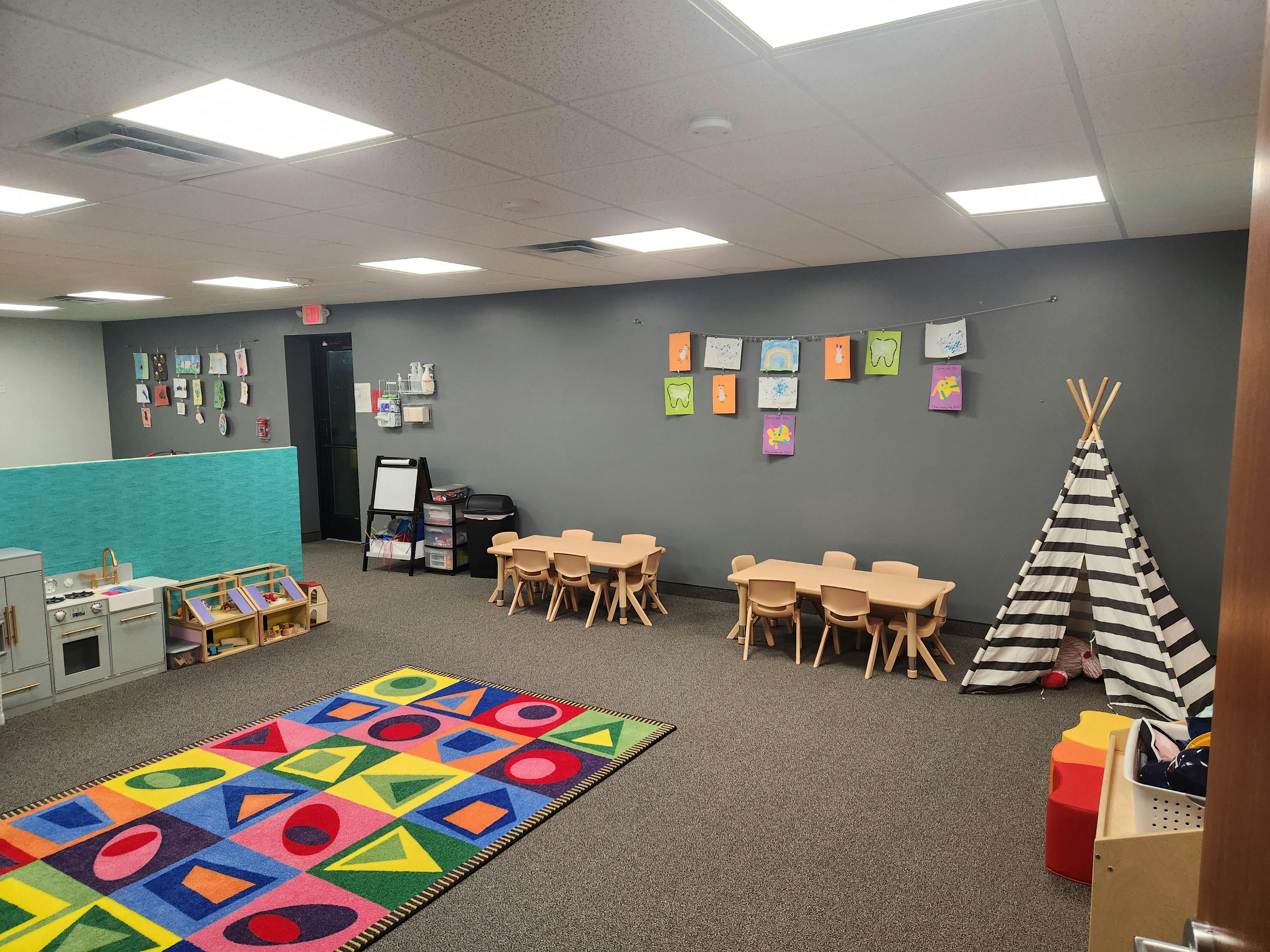 Children's play area with small tables, chairs, and a colorful rug