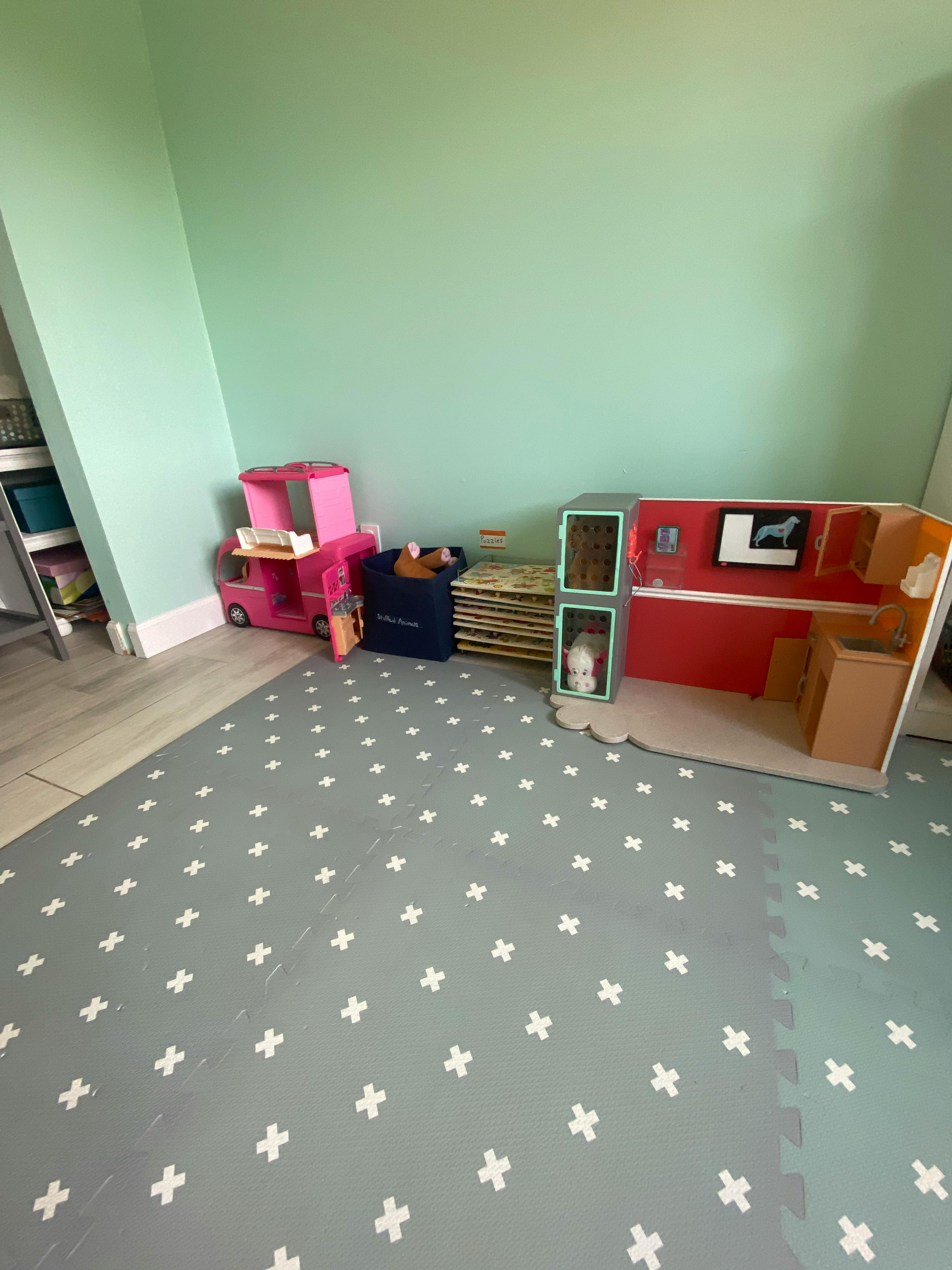 Playroom with a pink toy truck and a dollhouse on a gray mat