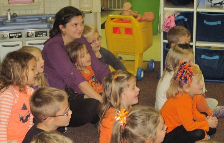 Adult person sitting on floor with multiple children around them