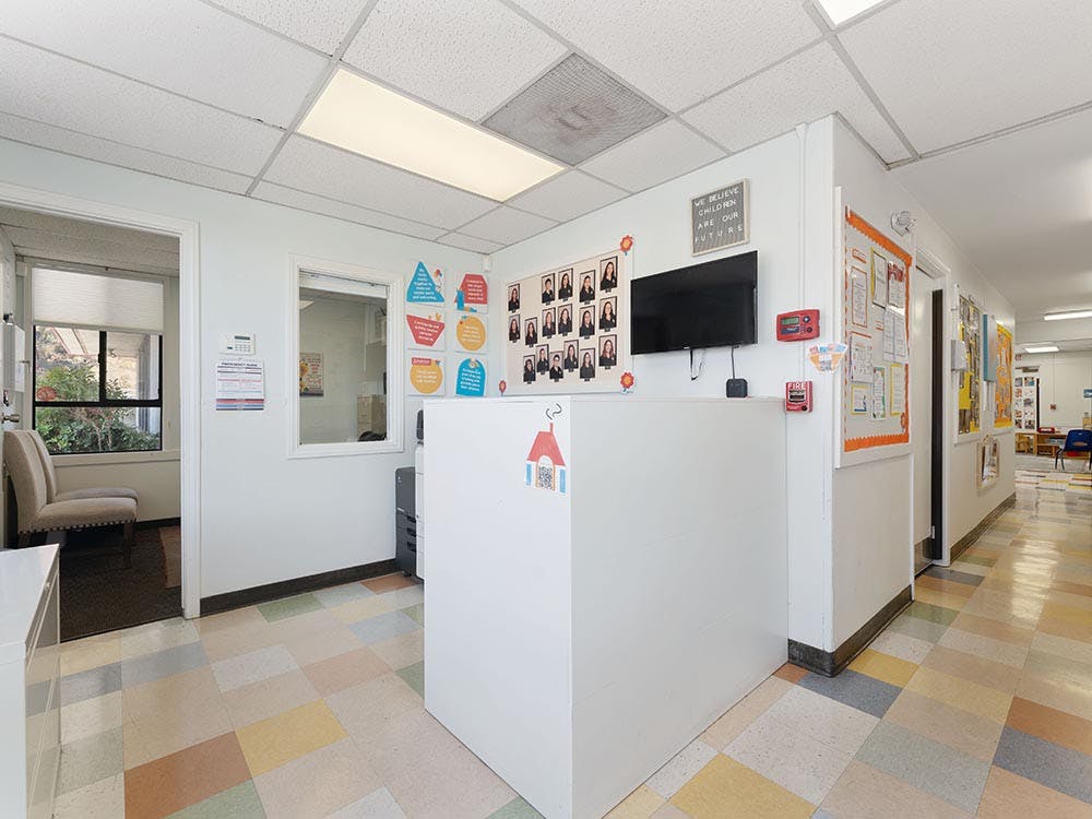 Reception desk in a brightly lit hallway with multicolored floor tiles