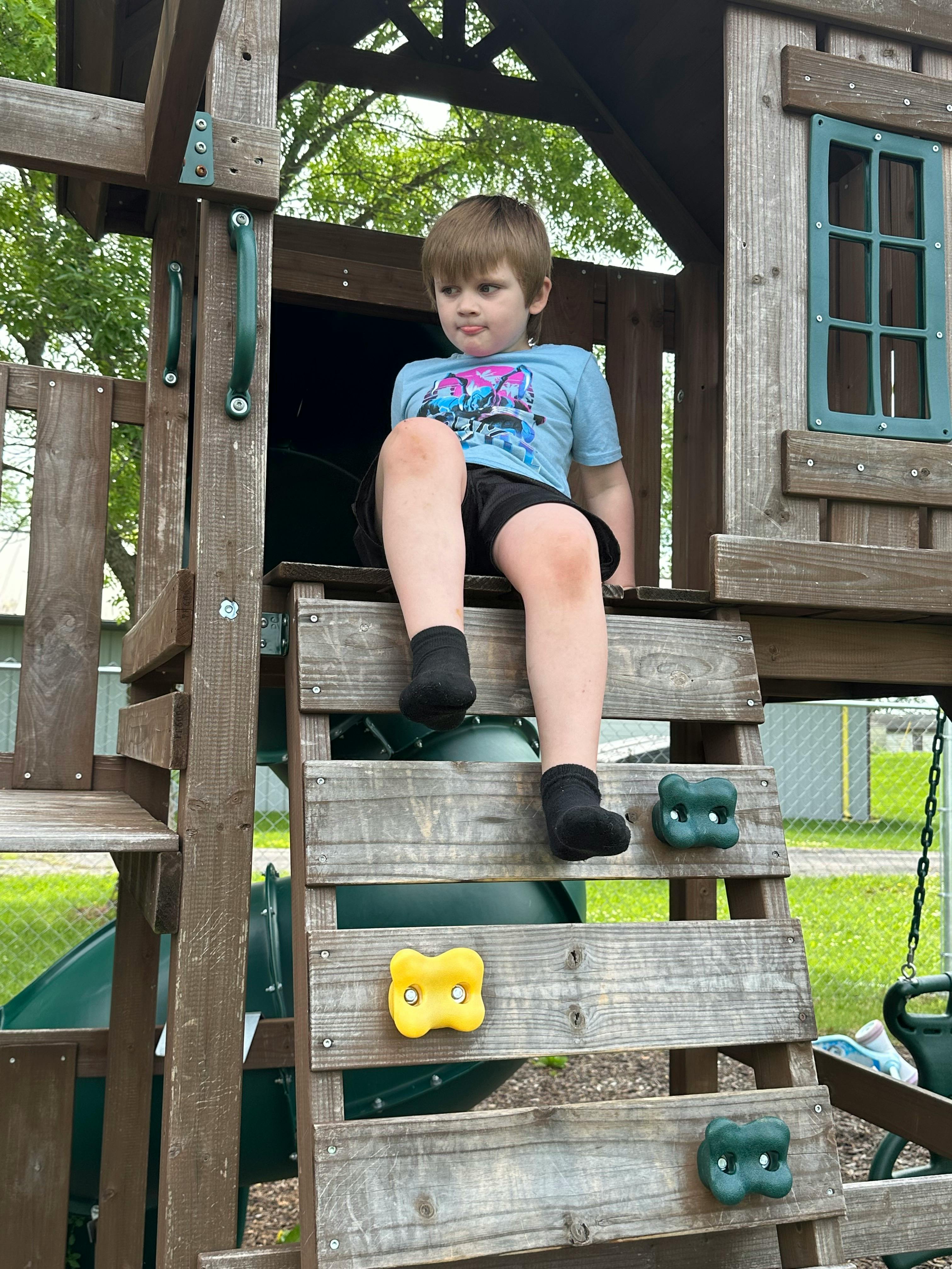 Child sitting on a wooden play structure