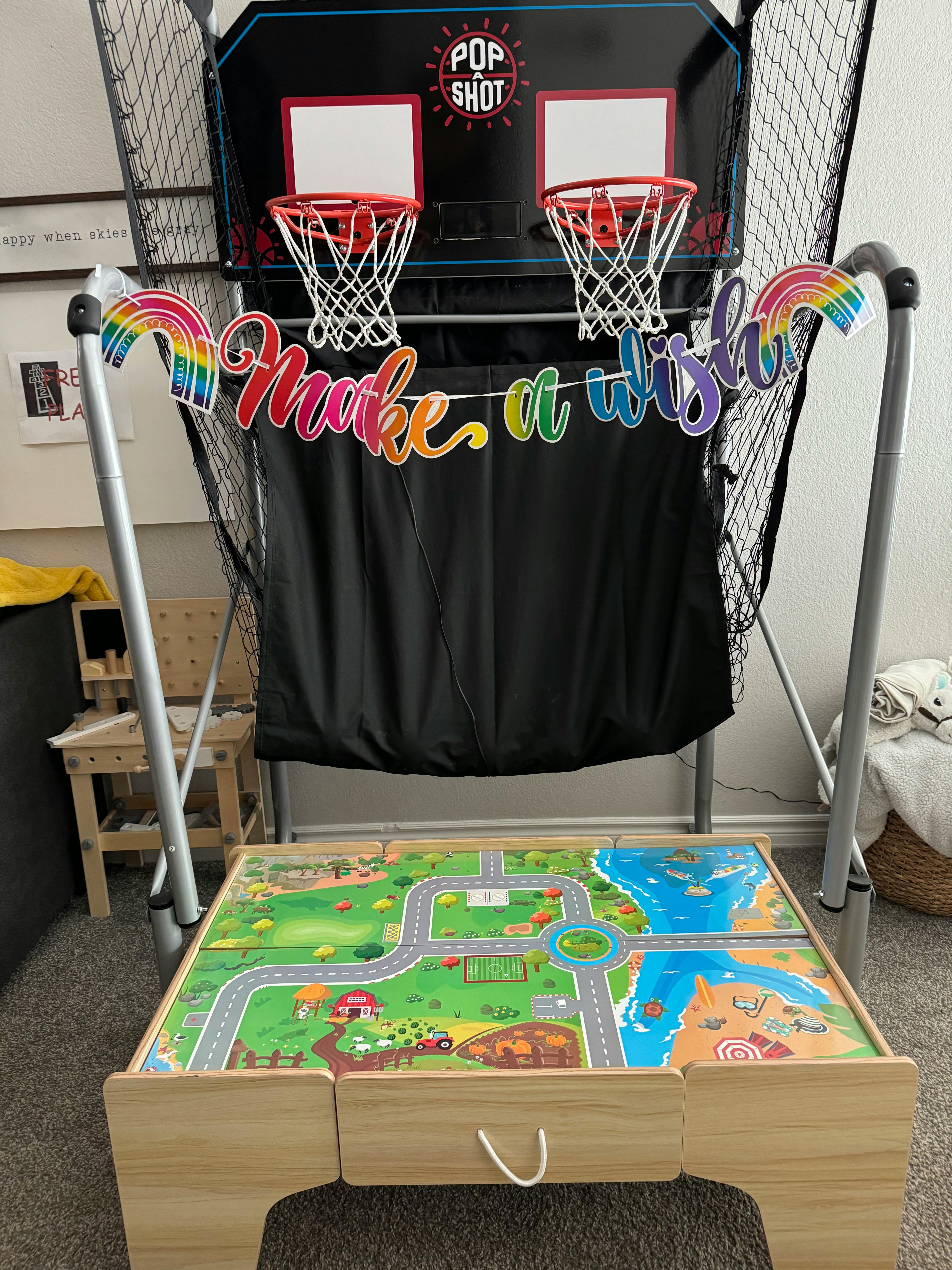 Basketball arcade game with a "Make a wish" banner and a playmat table