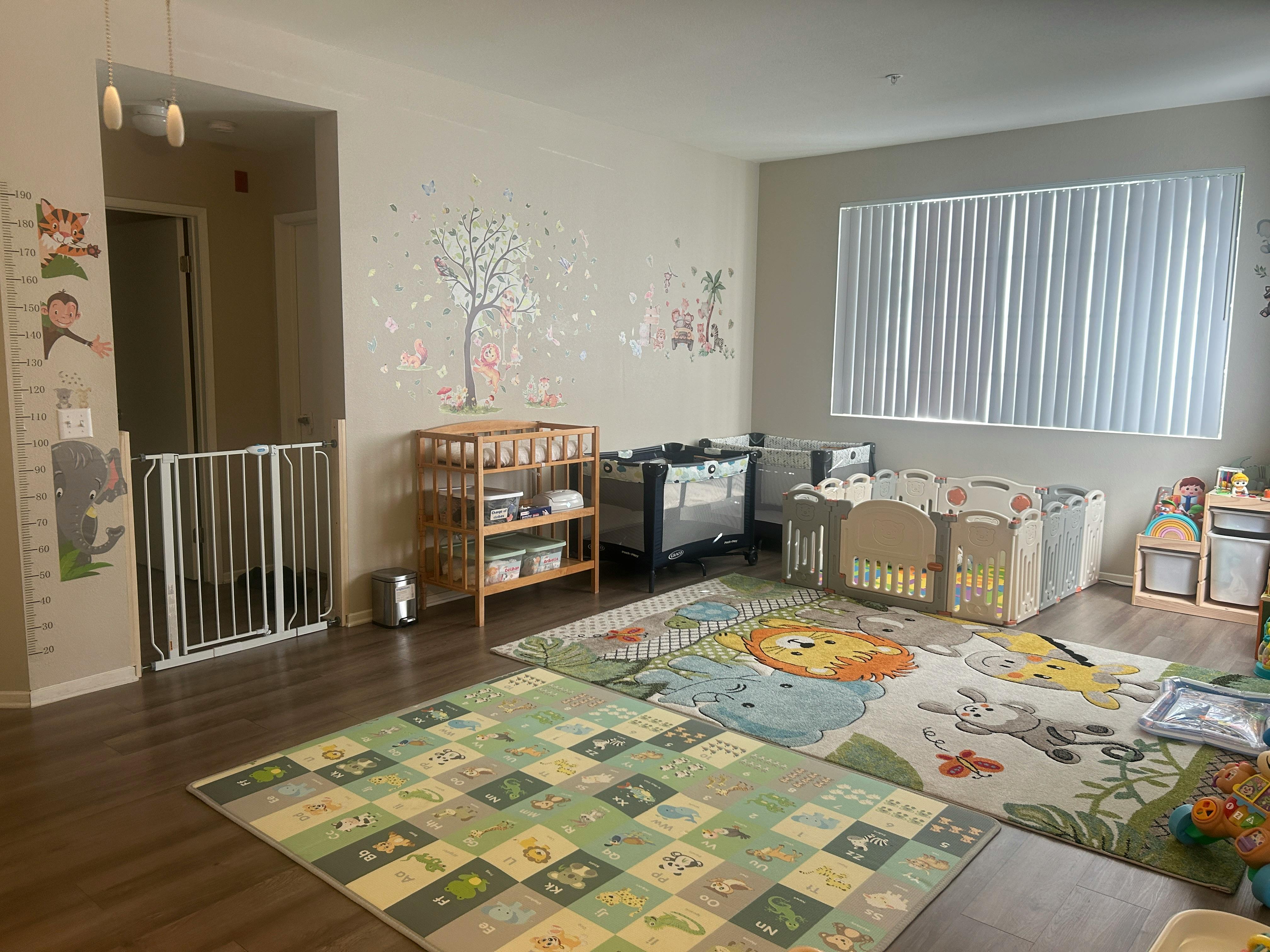 Nursery room with multiple cribs, changing table, and play mats