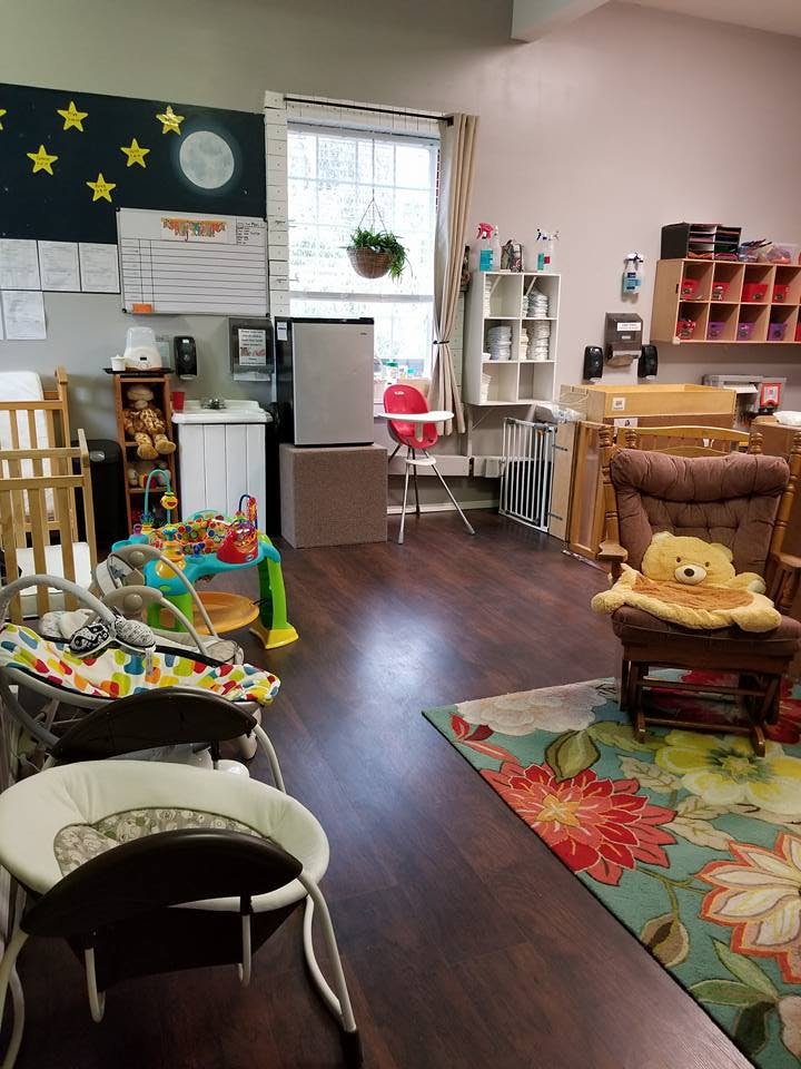 Daycare room with cribs, high chair, and play equipment