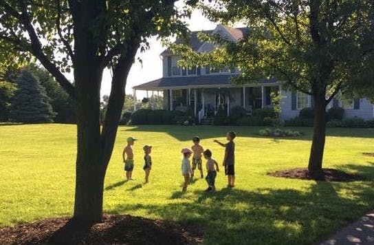 Children playing in a grassy yard in front of a house