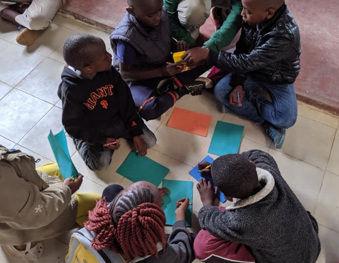 Children sitting on floor with colorful paper