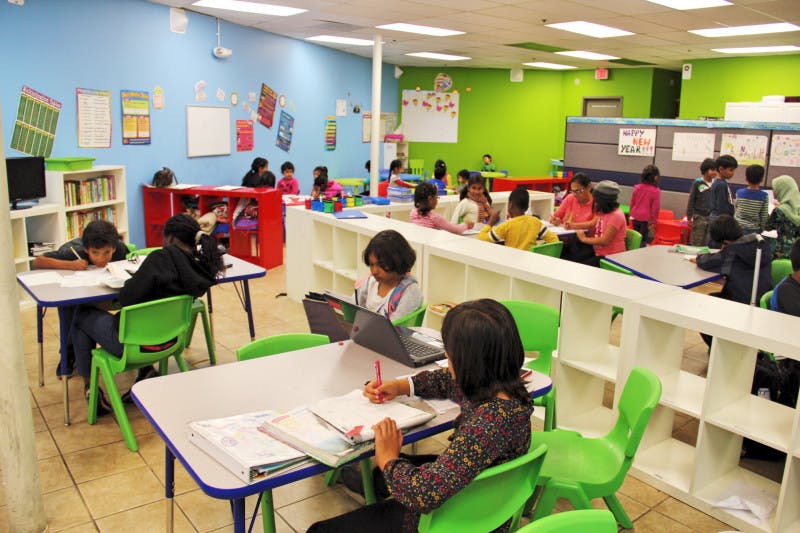 Children and adults working at desks in a classroom