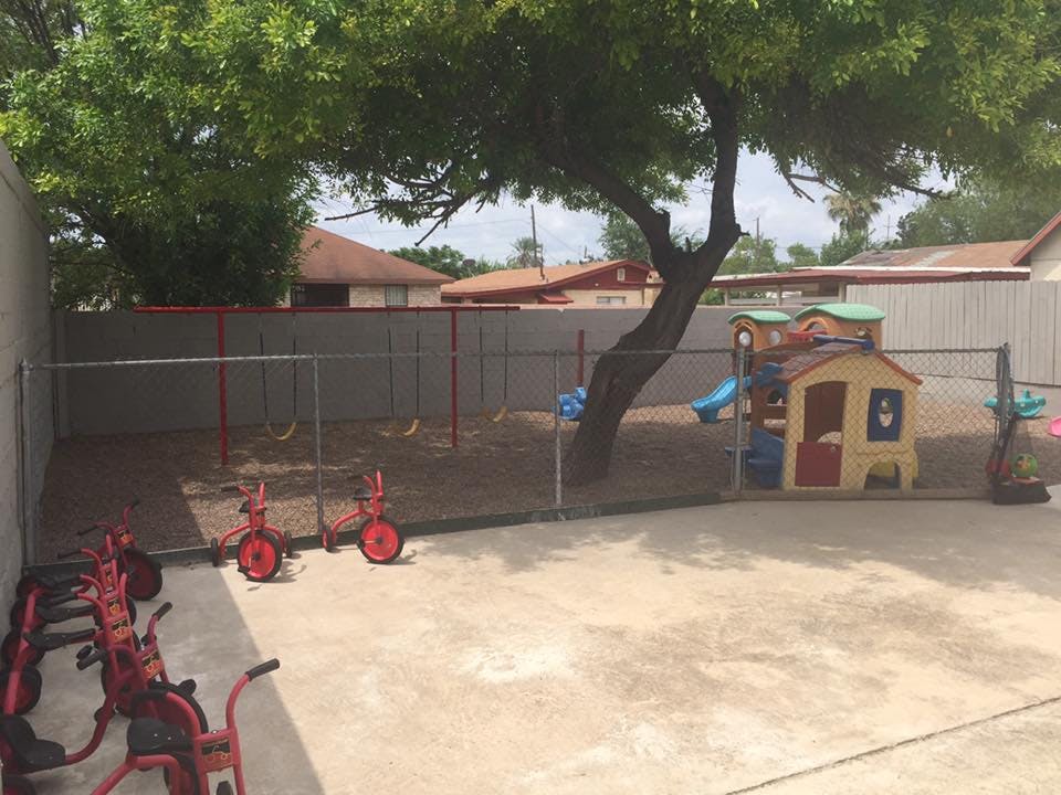 Outdoor playground with swings, playhouse, and tricycles