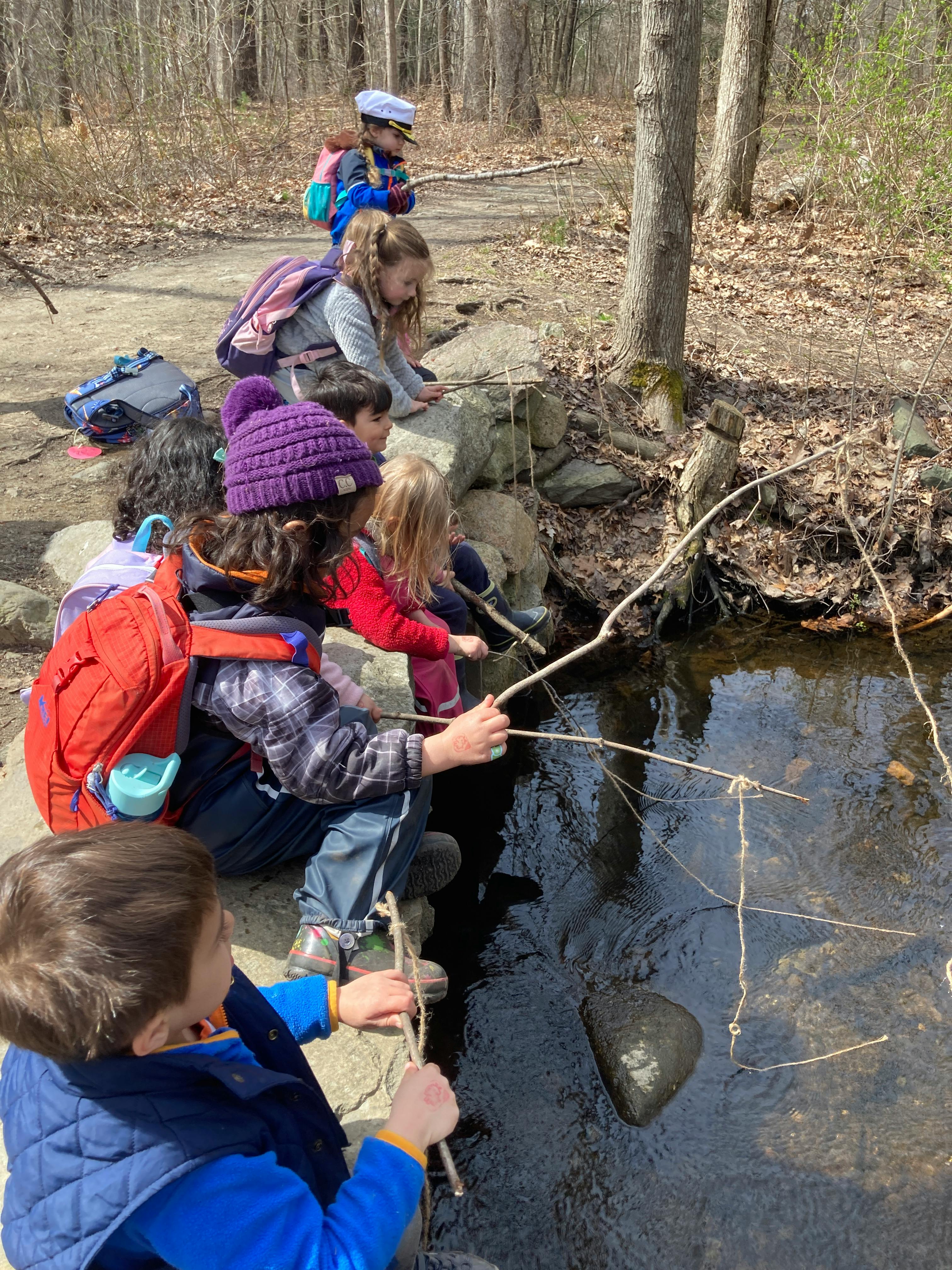 Children playing with sticks in a stream