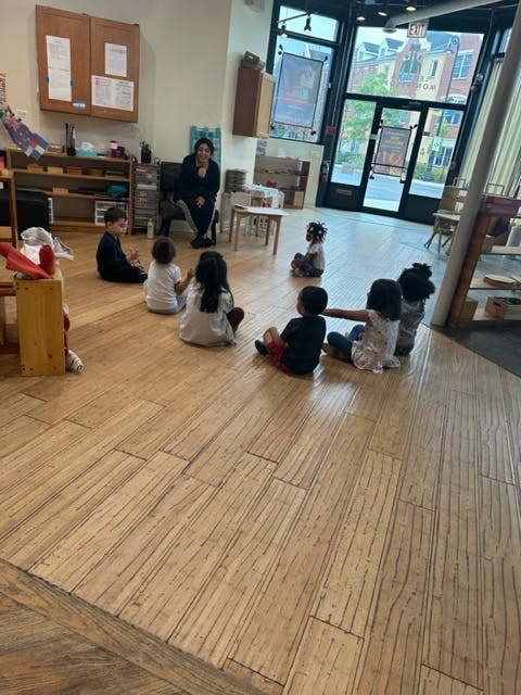 Adult and children sitting on the floor in a classroom