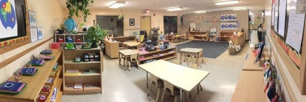 Empty classroom with small tables, chairs, and shelves