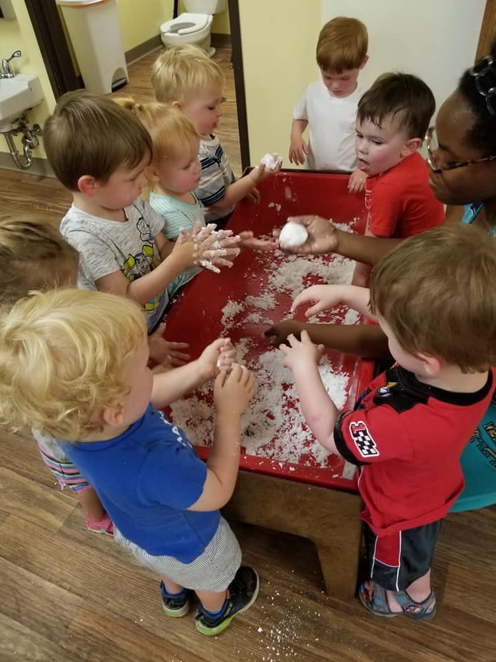 Children playing with a sensory bin filled with white material