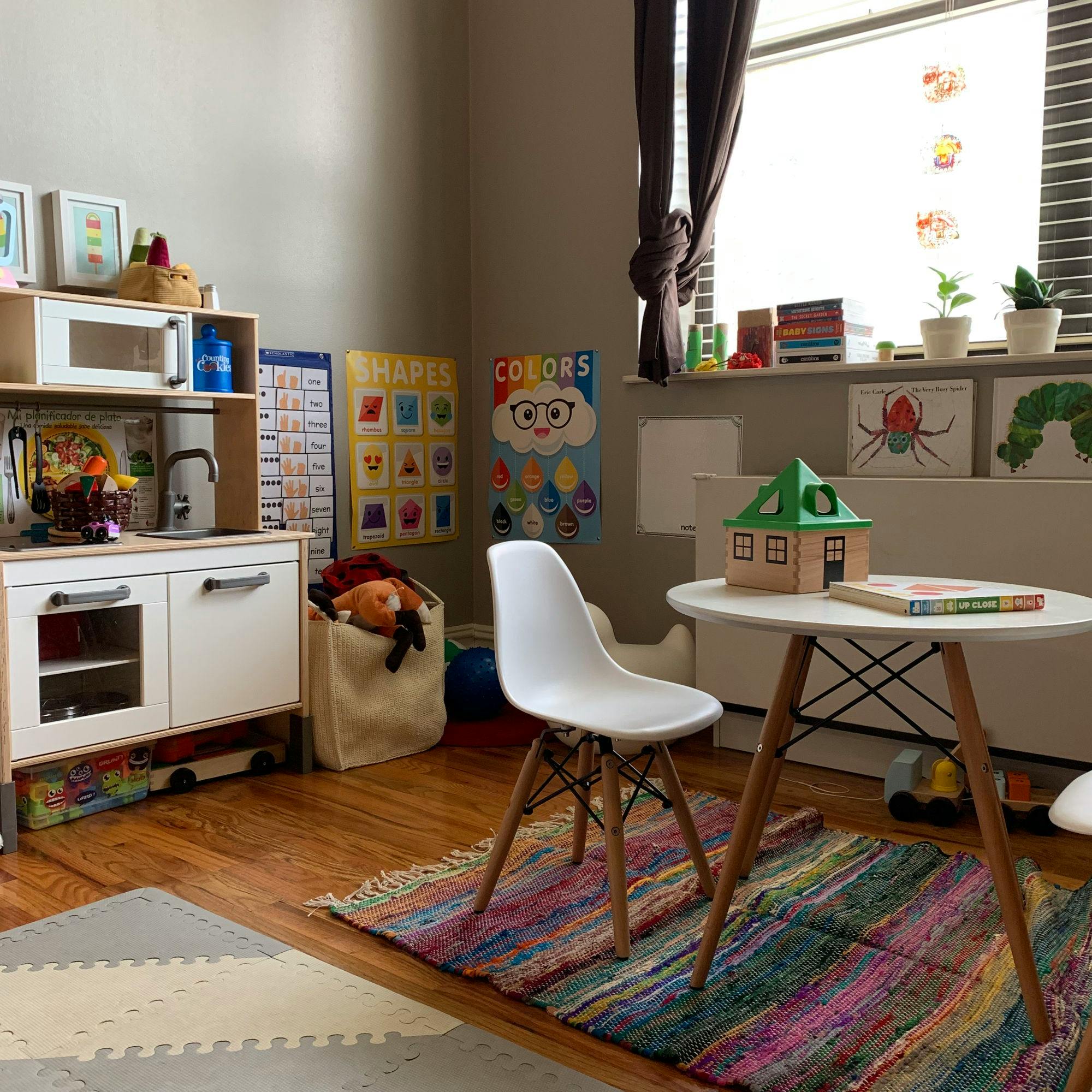 Playroom with toy kitchen, small table and chair, and educational posters