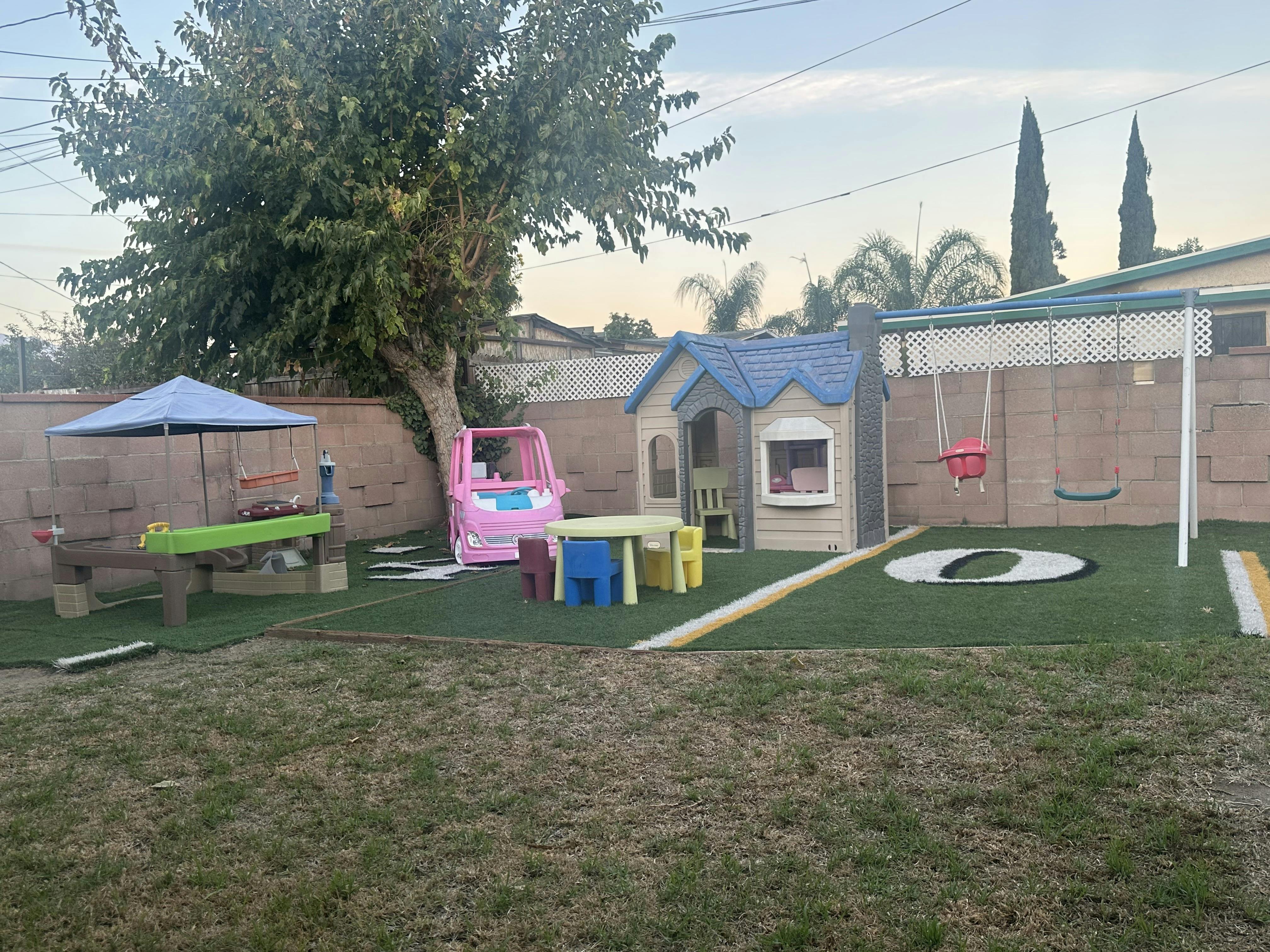 Backyard with playhouse, swing set, and children's table and chairs