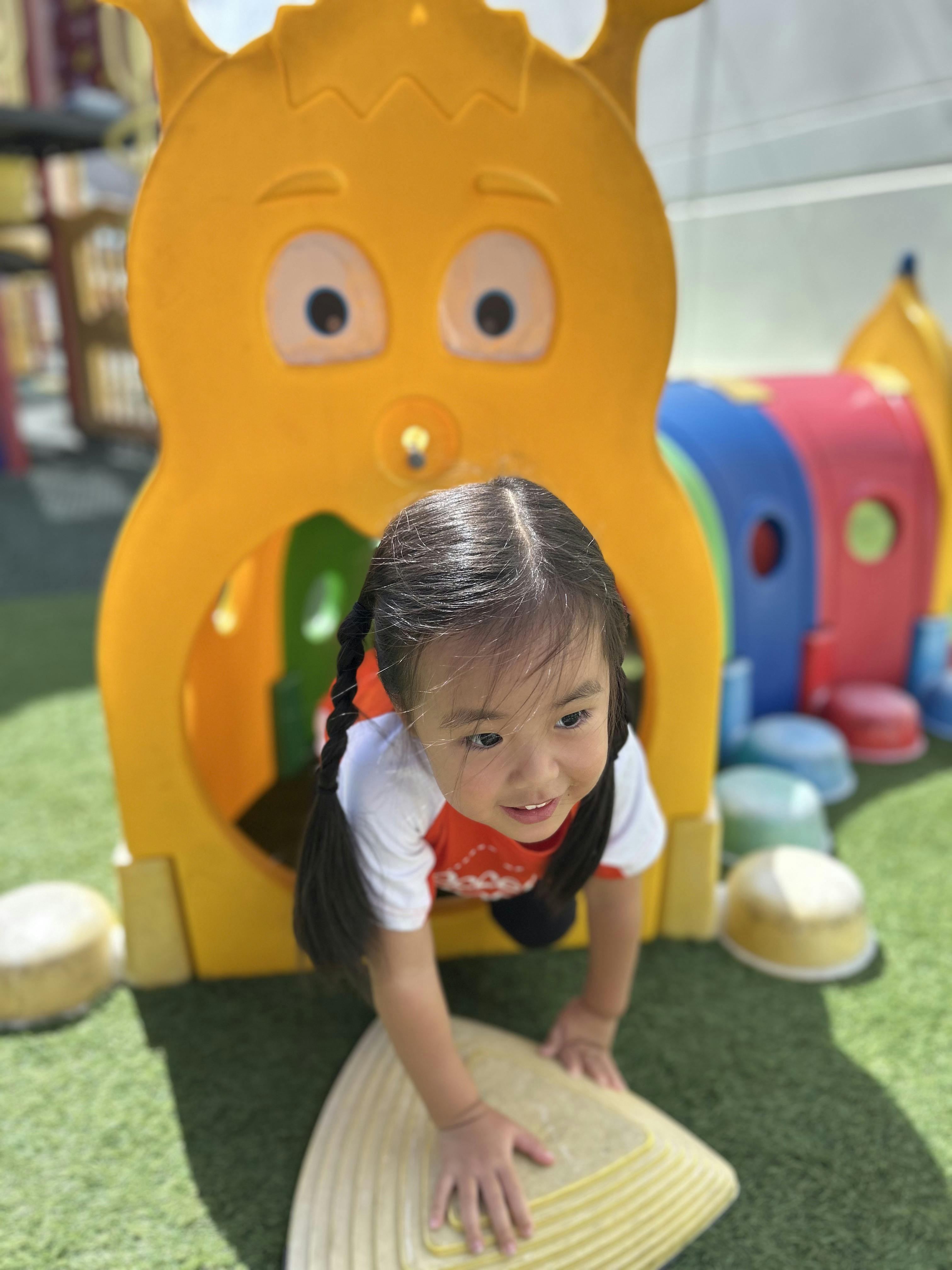 Child crawling out of a yellow play structure on a playground