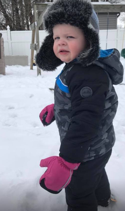 Child in a winter hat and coat standing in snow
