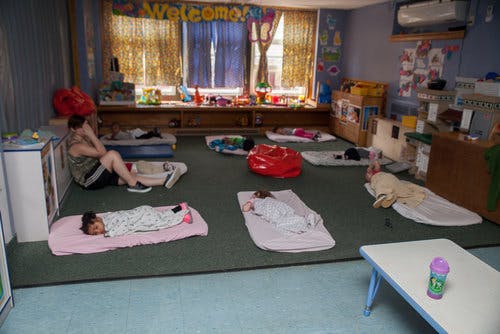Children sleeping on mats in a classroom