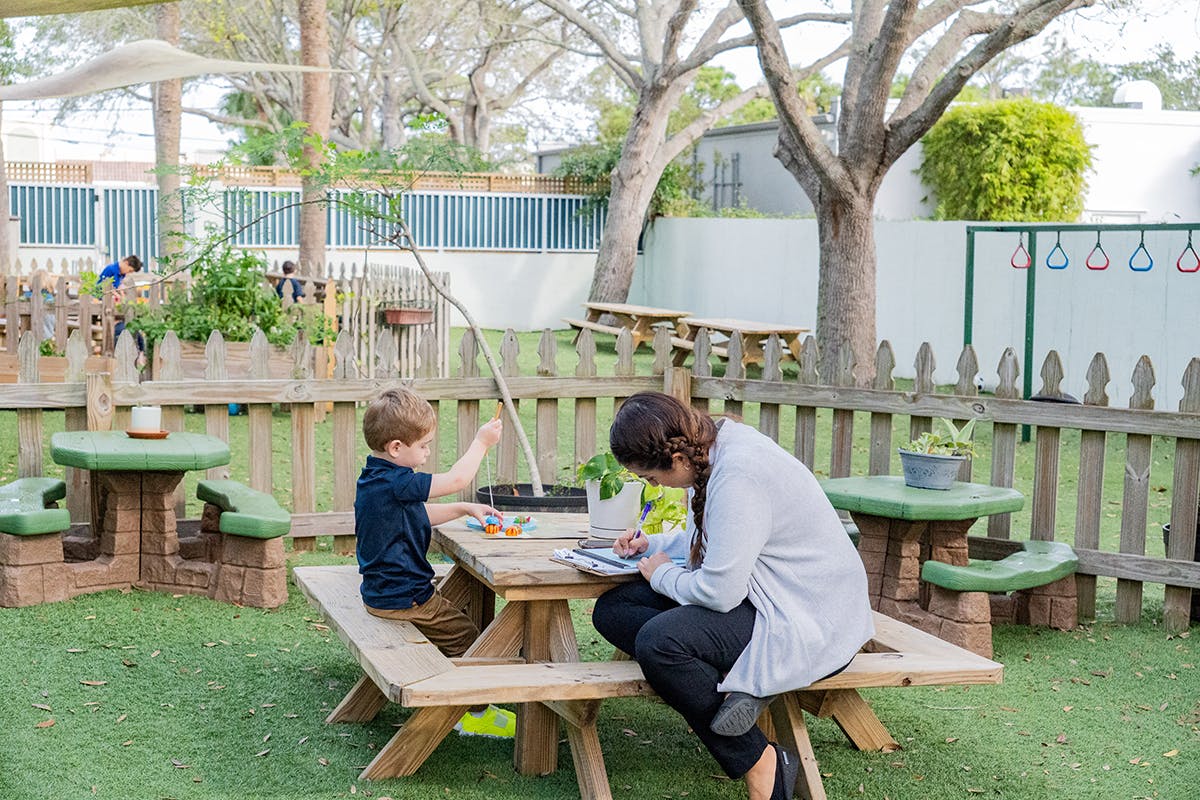 Adult and child sitting at a picnic table outdoors