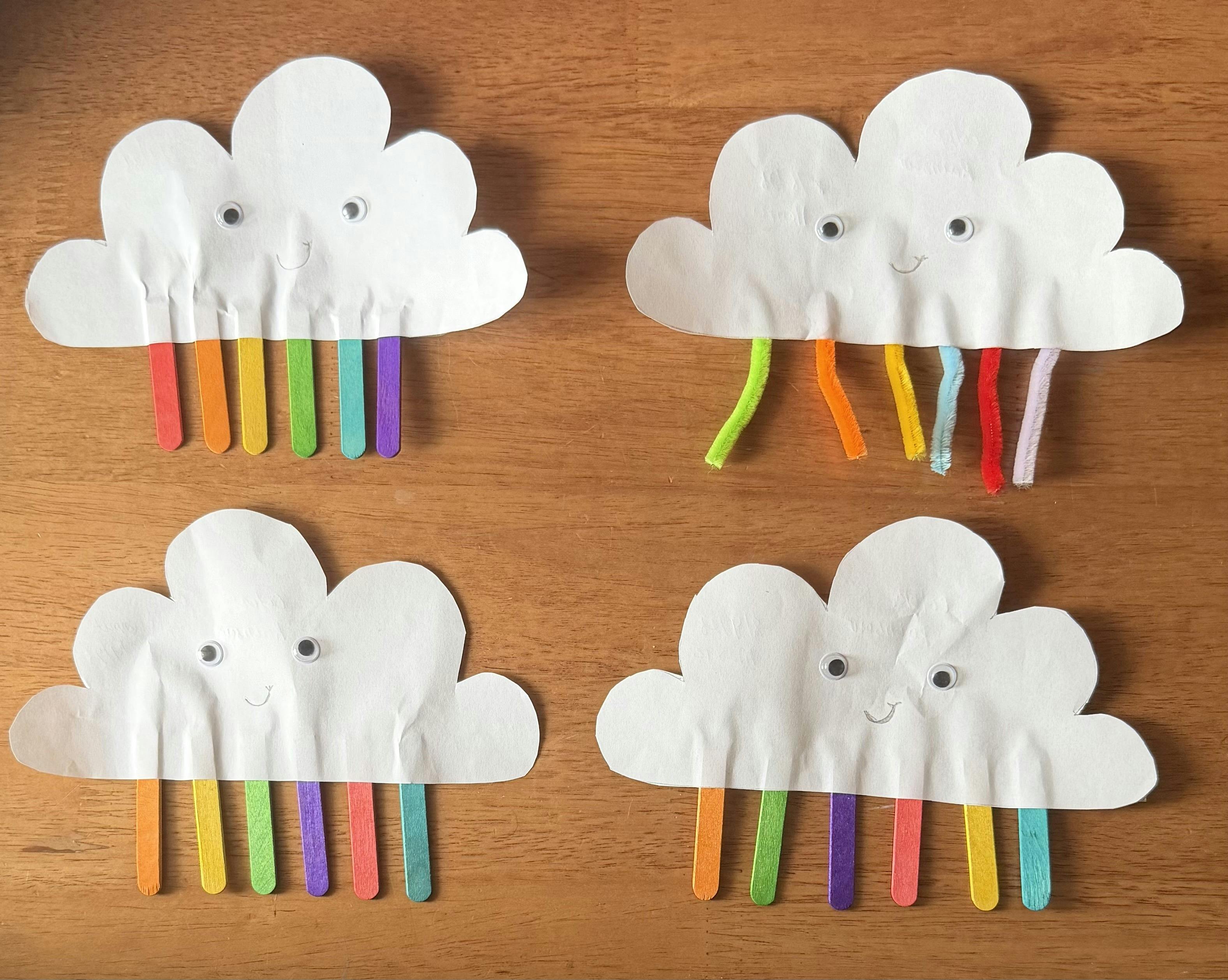 Four paper cloud crafts with googly eyes and colorful stick or pipe cleaner rays