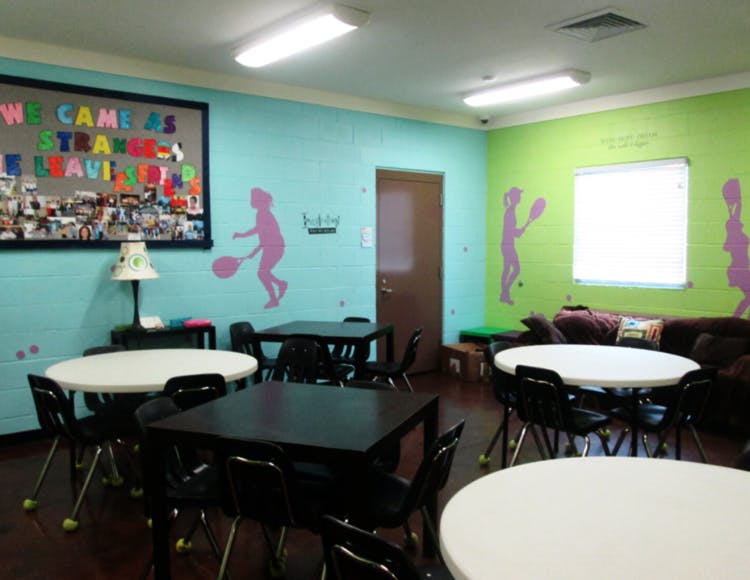 Room with tables and chairs, bulletin board, and wall decals
