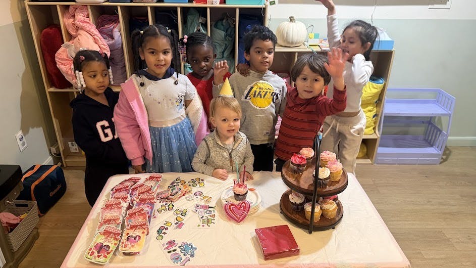 Children celebrating around a table with cupcakes and party decorations
